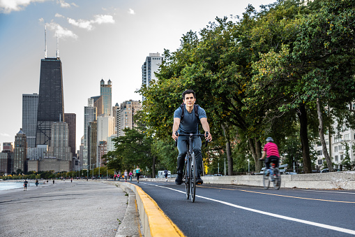 Young man cycling in Chicago by Michigan lake, commuting to work, United States.